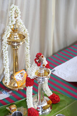 two brass and silver lamps are decorated with jasmine flower  garlands in a religious function