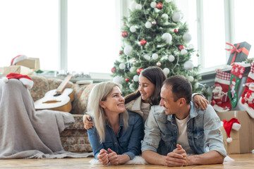 happy family mother, father and child daughter near Christmas tree at home
