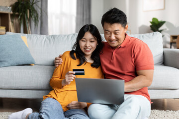 Fototapeta premium Relaxed japanese spouses using notebook and credit card