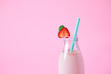 Close-up strawberry smoothie or milkshake in glass jar with berries on pink background. Summer drink