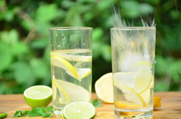 Fresh summer drink. Cold lemonade with mint lemon and lime on a nature outdoor background. Mojito summer refreshing cocktail with ice and mint