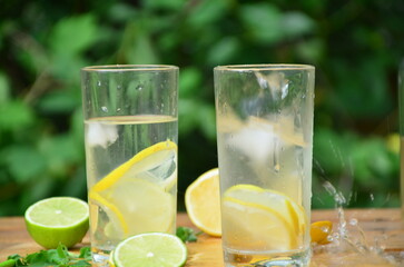 Fresh summer drink. Cold lemonade with mint lemon and lime on a nature outdoor background. Mojito summer refreshing cocktail with ice and mint