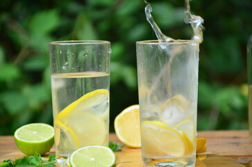 Fresh summer drink. Cold lemonade with mint lemon and lime on a nature outdoor background. Mojito summer refreshing cocktail with ice and mint