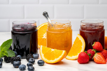 Fototapeta na wymiar Jam in jar and berries strawberry apricot orange, blueberries blackberries