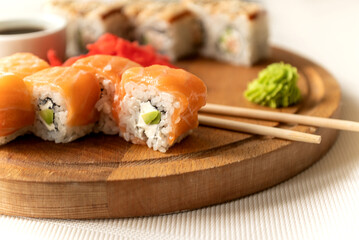 Set of delicious salmon philadelphia sushi roll served with wasabi cream and chopstick on wooden board