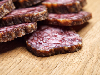 Closeup shot of sliced salami on the table. Pieces of delicious smoked sausage on a wooden cutting board.