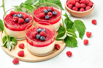 Raspberry Panna cotta with raspberry jelly on a light background. Berry dessert with cream sauce in...