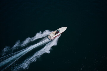big speedboat moving fast on dark water. A large speed boat of red white color moves diagonally on the water. Super speedboat with man fast moving diagonally on the water.