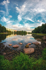 Evening on the Big Angarsky pond with stones, cloudy sky reflecting in water, Moscow, Russia