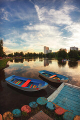 Fototapeta na wymiar Boats on the Big Angarsky pond, cloudy sky reflecting in water, in the evening, Moscow, Russia