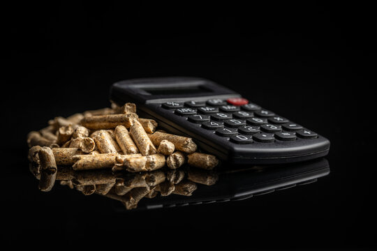 Wooden pellets and calculator on black background. The concept of paying for heating.