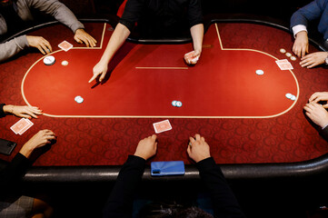 top view of men and women playing poker in casino