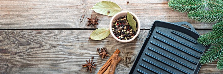 Traditional Christmas spices for cooking and drink (mulled wine) on a wooden background with fir branches. Festive atmosphere, copy space, banner.