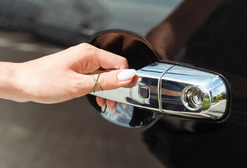 Keyless access to the car, female hand holding a handle of the car.