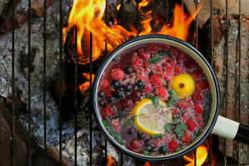 cook tea on a campfire, cook fruit tea on an open fire, mulled wine, compote boiled on a fire in...