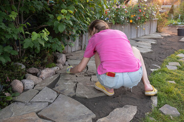 girl builder laying and grouting York stone paving slabs outdoors, DIY home patio project , finland...