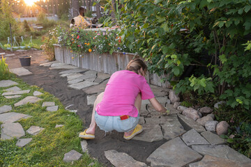 girl builder laying and grouting York stone paving slabs outdoors, DIY home patio project , finland...
