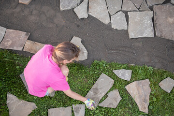 girl builder laying and grouting York stone paving slabs outdoors, DIY home patio project , finland scandinavia, landscaping around a wooden house, Hygge with your own hands
