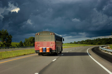 Camper Bus drive the highway towards ominous clouds.