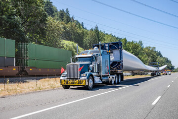 Big rig semi truck tractor with oversize load sign on the front transporting windmill electric...