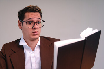 An elegant man with a surprised face reading a book. Business man reading a book. Caucasian blond man dressed in a suit