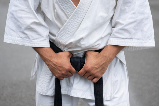 Kimono close-up. The karateka keeps his hands on the black belt of his kimono.