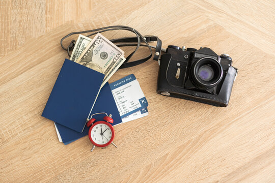 Top view photo of camera, passport, tickets on light colored wooden floor
