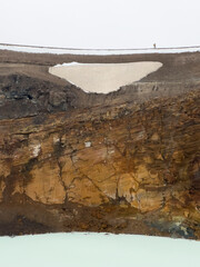 A hiker walking on the edge of the volcanic crater of Víti in in the Askja caldera in Iceland