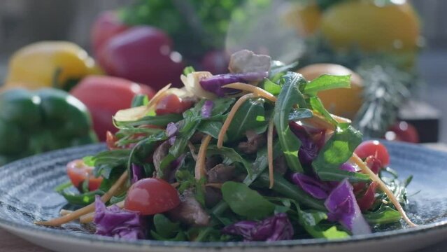 Close-up of fresh salad made of red cabbige, tomatoes, onions, basil, arugula and pieces of fried meat