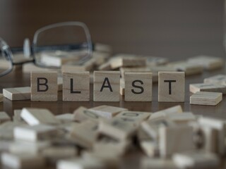 blast word or concept represented by wooden letter tiles on a wooden table with glasses and a book