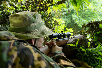 The sniper looks into the scope of his rifle. Sniper at the firing point in position. Shooter in...