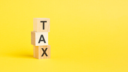 TAX text on wooden block with white backgrounds.