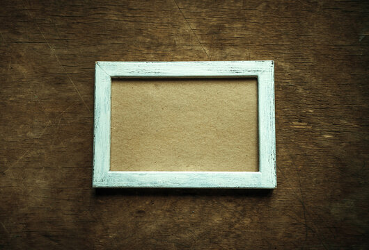 A white photo frame in the style of shabby chic on a wooden table. Vintage photo frame. Photo design in retro style.