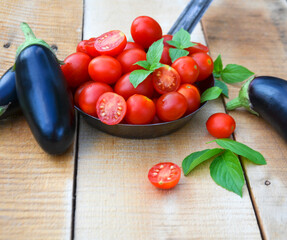 fresh vegetables eggplant and tomatoes next to basil leaves on wooden boards selective focus
