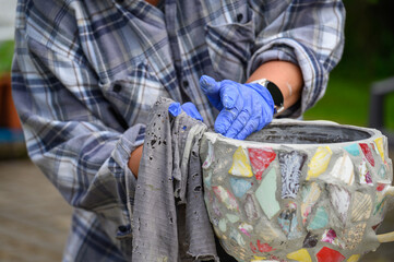 People decorate earthenware with mosaic techniques in the master class or in the fresh air in the workshop. Homemade mosaic flower pot with porcelain pieces.