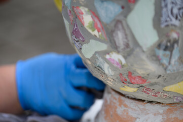 People decorate earthenware with mosaic techniques in the master class or in the fresh air in the workshop. Homemade mosaic flower pot with porcelain pieces.