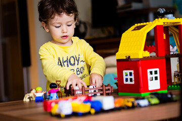 Baby boy playing with construction toy blocks at home. Kids playing. Children at day care. Child...