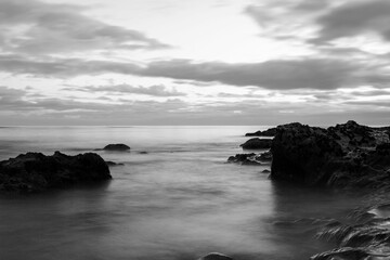 Grayscale of coastal rocks in the ocean on a cloudy day