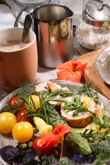 Country breakfast concept with bread, kitchen garden vegetables, herbs and edible flowers, coffee and milk.