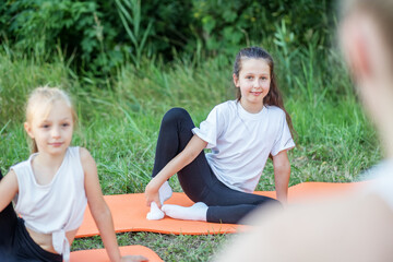 Children play sports in park using fitness mats. Training with gymnastics or aerobics