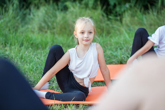 Children play sports in park using fitness mats. Training with gymnastics or aerobics