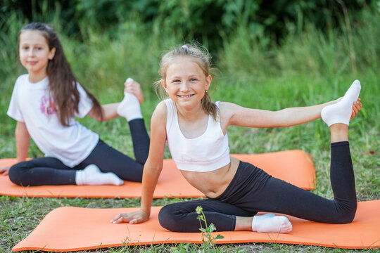 Children play sports in park using fitness mats. Training with gymnastics or aerobics