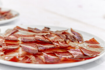 Close-up of a plate of iberian ham on a white plate. Typical spanish food. Selective focus