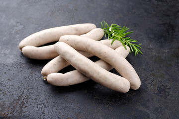 Traditionelle rohe Schweinsbratwurst angeboten als close-up auf einem rustikalen schwarzen Board mit Textfreiraum  © HLPhoto