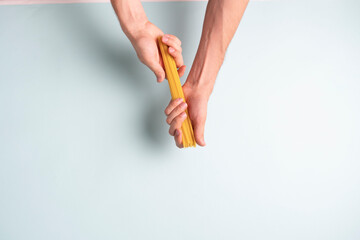 a cook's hand break italian raw spaghetti pasta before preparation