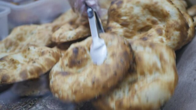 baker using tongs to place hot pastries in a plastic bag to a customer. The process of trading bread in a bakery