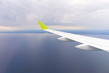 Wing of an airborne airplane ocean below. the plane flies over the water. clear blue sky. close up