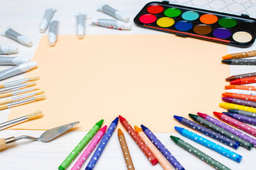 Watercolor oil paints, paintbrushes, colorful pencils, pastel crayons,blank watercolor paper pad. Creativity creation process. Artist's stuff on white table.Top view Flatlay of drawing supplies