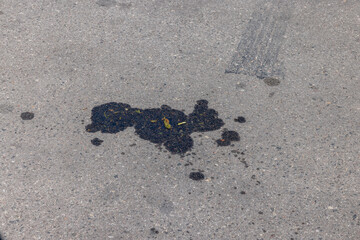 A road for vehicles covered with stains and pollution from oil and fuel of cars
