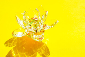 Beautiful crystal lotus flower on a yellow sunny table